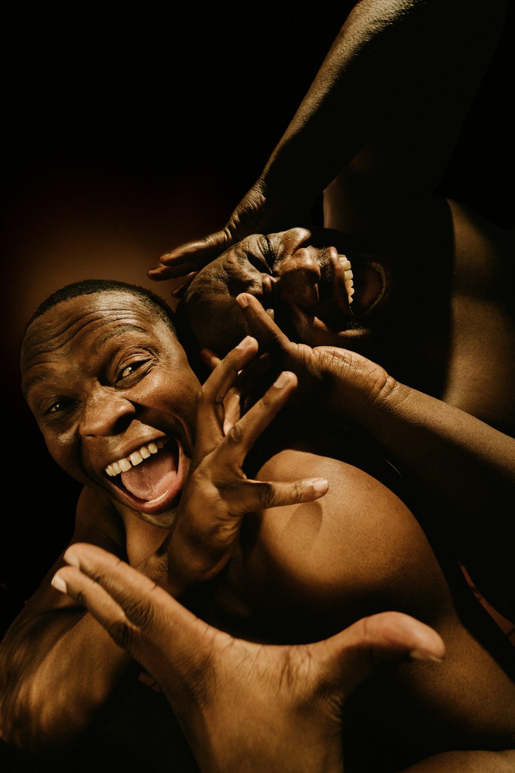 Porträt von zwei schwarzen Männern, die sich ausgelassen bewegen, in die Kamera lachen und brüllen.