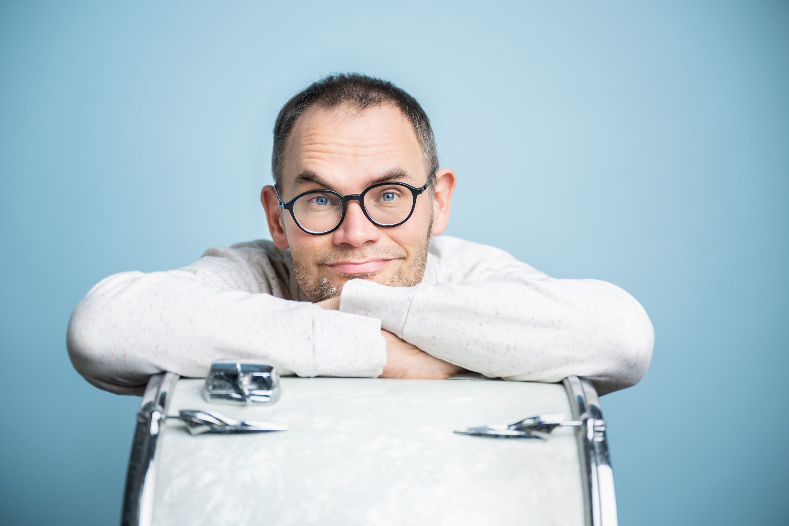 Portrait von Henning Luther, der mit der Trommel seines Schlagzeugs posiert.