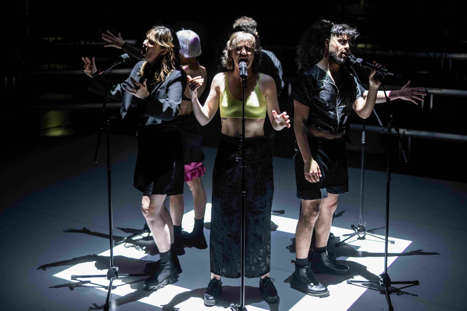 Sechs Performer*innen von Club Gewalt beim 10-jährigen Jubiläum des Kollektivs. Sie singen oder rufen im Kreis stehend in Mikrofone.