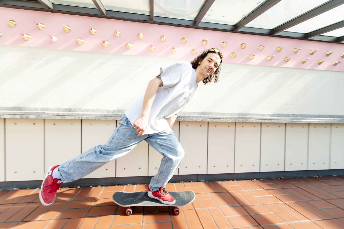 Porträt von Gustavo, der auf einem Skateboard durch die Neuköllner Oper fährt.